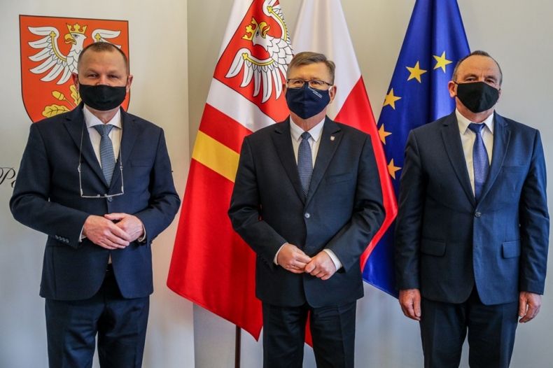 Marszałek Witold Kozłowski stoi z uczestnikami spotkania. Z tyły widoczne flagi Małopolski i Unii Europejskiej.