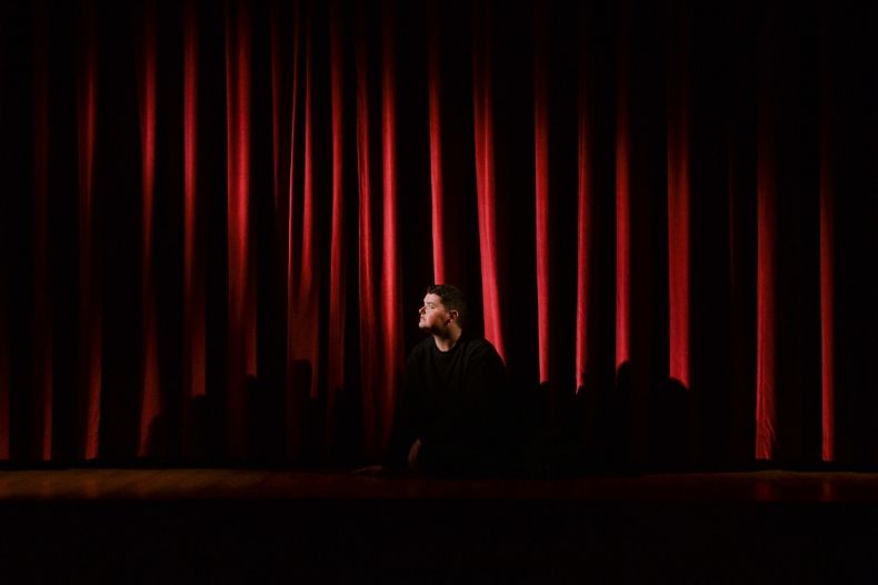 Mężczyzna na scenie teatralnej. Patrzy w reflektor