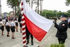 Strażacy wciągają na maszt biało-czerwoną flagę.