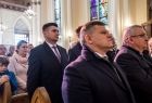 Wicemarszałek Łukasz Smółka stoi w kościele. Wokół ludzie.