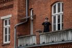Strażak hejnalista stoi na balkonie i gra na trąbce.