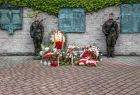 Wieńce złożone przed tablicą w muzeum. Obok stoi wojskowa warta honorowa.
