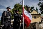 Strażacy OSP wciągają flagę Polski na maszt.
