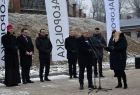 Minister Infrastruktury Andrzej Adamczyk przemawia do mikrofonu. Z tyłu widoczni pozostali uczestnicy wydarzenia i flagi z napisem Małopolska.