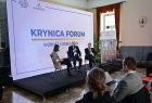 Uczestnicy debaty siedzą na krzesłach na tle ekranu z napisem "Krynica Forum"