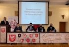 Wicemarszałek Łukasz Smółka i wojewoda Łukasz Kmita siedzą przy stole sali konferencyjnej. Z tyłu widoczny ekran.