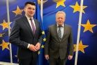 Wicemarszałek Łukasz Smółka stoi z komisarzem Januszem Wojciechowskim na tle flagi Unii Europejskiej.