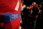 Grupa osób wchodzi do czerwonego namiotu z napisem "Małopolska Tarcza Antykryzysowa - pakiet medyczny"