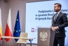 Minister Kamil Bortniczuk przemawia do zgromadzonych gości. W tle widoczny ekran i flagi Małopolski, Polski i Unii Europejskiej.