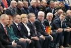 Siedzący na trybunach samorządowcy i ubrani na galowo przedstawiciele służb mundurowych.W pierwszym rzędzie w centralnym miejscu widać Marszałka Witolda Kozłowskiego po jego prawej stronie siedzi radny Stanisław Pasoń po lewej radna Marta Mordarska.