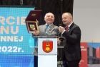 Starosta nowosądecki Marek Kwiatkowski i Wójt gminy Korzenna Leszek Skowron, stoją przy szarym pulpicie na którym w centralnym miejscu znajduję herb korzennej,. W tle widać niebieski panel, na którym znajduje się widoczny w połowie biały napis. 