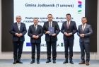 Marszałek Witold Kozłowski i wicemarszałkowie Łukasz Smółka i Józef Gawron stoją na scenie z przedstawicielem Gminy Jodłownik.