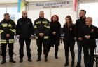 Wnętrze białego namiotu będącym hubem przesiadkowym dla uchodźców z Ukrainy. Wewnątrz widać m.in mężczyzn ubranych w odblaskowe stroje straży pożarnej, policji. W otoczeniu kobiet z lewej strony stoi starosta Olkuski. 