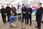 Marszałek Witold Kozłowski, starosta olkuski Bogumił Sobczyk w towarzystwie samorządowców i wolontariuszy. Mężczyźni stoją wewnątrz białego namiotu, przed marszałkiem Witoldem Kozłowskim znajdują się 2 mikrofony. W tle widać napis małopolska. 
