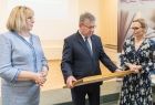 Marszałek Witold Kozłowski wręcza stojącej po jego lewej stronie dyrektor Alinie Marek nagrodę Polonie Minor. Marszałek trzyma oprawioną w złota ramę polonię w obu rękach. Z prawej strony marszałka stoi radna Marta Mordarska. 
