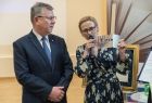 Dyrektor biblioteki Alina Marek, trzyma w ręku metalową statuetkę "Przyjaciela Biblioteki", którą wręcza stojącemu obok Marszałkowi Witoldowi Kozłowskiemu. 