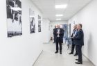 Widok na zdjęcia sportowców wiszących na ścianie korytarza Katedry Fizjologii Wysiłku i Bioenergetyki Mięśni - Marszałek Kozłowski ogląda zdjęcia. 