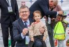 Widok na Marszałka Witolda Kozłowskiego prezentującego zawieszony na piersi dziecka pamiątkowy medal z imprezy kolarskiej
