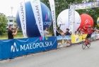 meta wyścigu - po lewej stronie szosy banery z logiem Małopolski - po środku zwycięzca wyścigu mijający metę