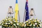 widok na dzwony kościelne Sanktuarium z przodu dwa duże bukiety z lilii i dwie flagi