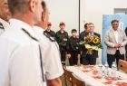 Marszałek Witold Kozłowski stojący na drugim planie z kwiatami w otoczeniu strażaków na nowej remizie