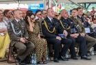 Uczestnicy Wojewódzkich Dożynek, siedzą na krzesłach pod zadaszeniem, część zgromadzonych osób ma na sobie galowe mundury,. 