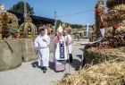 Metropolita Krakowski abp. Marek Jędraszewski ogląda ustawione na balach słomy wieńce dożynkowe ustawione po obu stronach alejki. 