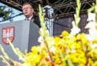 Marszałek Witold Kozłowski stoi na scenie, przy pulpicie na którym umieszczono herb Małopolski. U podnóża sceny widać bukiet wykonany ze zboża i żółtych kwiatów. 