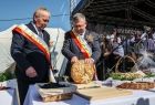 Marszałek Witold Kozłowski w towarzystwie drugiej osoby kroi chleb dożynkowy