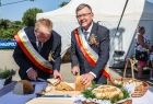 Marszałek Witold Kozłowski w towarzystwie drugiej osoby kroi chleb dożynkowy