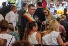 Marszałek Witold Kozłowski częstuje pokrojonym chlebem dożynkowym zaproszonych gości