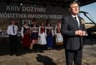 na scenie Dożynek Małopolskich marszałek Witold Kozłowski przemawiający do publiczności. W tle zespół w strojach regionalnych.