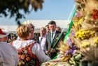 Marszałek Łukasz Smółka w otoczeniu uczestników Dożynek Wojewódzkich na pierwszym planie wieniec dożynkowy
