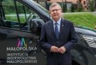 Marszałek Witold Kozłowski stoi przy czarnym busie z logiem województwa małopolskiego.