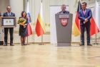 Marszałek małopolski Witold Kozłowski stoi przy mównicy w otoczeniu przedstawiciele władz samorządowych z Małopolski i Turyngii. Jedna z osób trzyma Medal Polonia Minor. 