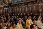 Uczestnicy mszy świętej siedzą w rzędach słuchając kazania