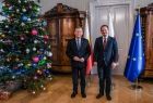 Marszałek Witold Kozłowski stoi wraz z konsulem w gabinecie. W tle widoczna flaga Unii Europejskiej, obok stoi choinka.