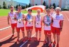 Grupa młodzieży w strojach sportowych stoi na bieżni trzymając biało-czerwoną flagę