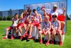 Grupa młodych sportowców pozuje do wspólnego zdjęcia na tle zielonej murawy