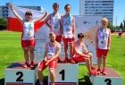 Młodzi sportowcy w biało-czerwonych strojach pozują do wspólnego zdjęcia siedząc na różnych stopniach podium