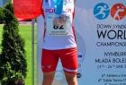 Zawodnik stoi na stopniu podium, trzymając biało-czerwoną flagę