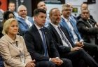Wicemarszałek Łukasz Smółka siedzi na widowni, obok inni ludzie.