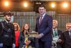 Wicemarszałek Łukasz Smółka odbiera od strażaka pamiątkowy toporek.