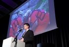 Wicemarszałek Łukasz Smółka przemawia do uczestników wydarzenia. Za nim widoczny ekran z ratownikami.