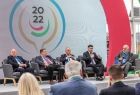 Wicemarszałek Łukasz Smółka siedzi wśród prelegentów. Na pierwszym planie widocznie ludzie siedzący na widowni.