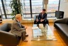 Wicemarszałek Łukasz Smółka siedzi z komisarzem Januszem Wojciechowskim na fotelach w biurze. Z tyłu widoczny telewizor, kwiat i duże okno.