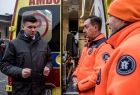 Wicemarszałek Łukasz Smółka rozmawia z ratownikami medycznymi przy karetce.