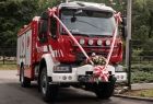 Nowy wóz strażacki udekorowany biało-czerwoną szarfą.