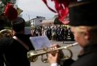 Członek górniczej orkiestry grający na trąbce. W tle uczestnicy obchodów stojący w szeregu na placu 