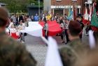 Szeroko rozpostarta biało-czerwona flaga i trzymające ją dzieci